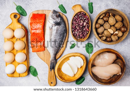 Assortment of healthy protein source and body building food. Salmon, chicken breast, eggs, mozzarella cheese, beans, nuts, spinach, flax and chia seeds. Top view. light background