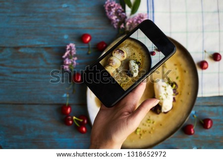 Taking photo of Cottage cheese pancakes, syrniki, close-up. Woman hands with smartphone taking photo of breakfast food on wooden table background 