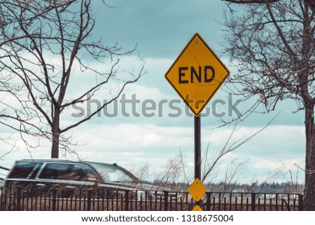 Yellow End road sign and moving car in the background