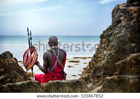 Maasai sitting by the ocean on the beach Royalty-Free Stock Photo #131867852