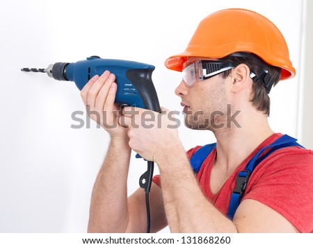 Portrait of a man drilling a hole in the wall.
