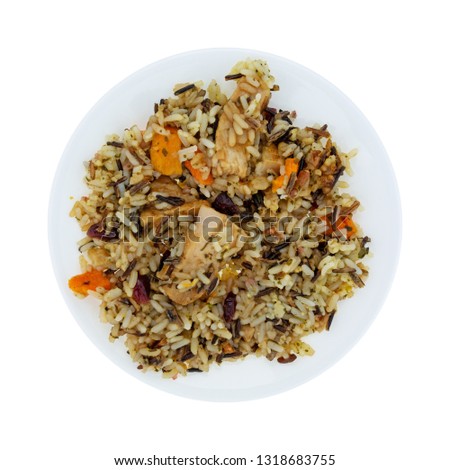 Overhead view of chicken with pecans and wild rice on a plate isolated on a white background.