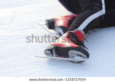 feet in skates of a fallen man on an ice rink
