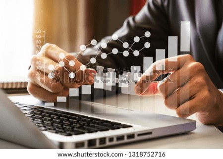 Business solutions and success concept. Businessman hand connecting jigsaw puzzle with icon graph at office in morning light
