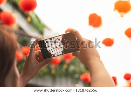 Woman using smart phone take a picture to red lantern.