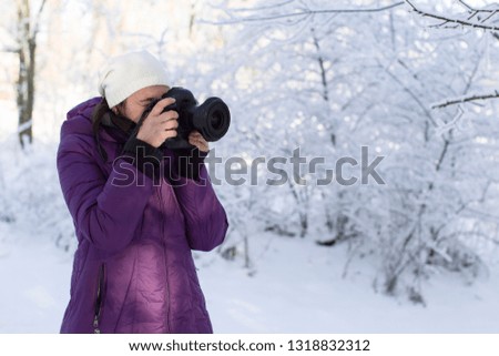 Woman with a camera on a winter background. Take pictures of nature