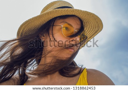 Happy girl on vacation. Young brunette in a straw hat and sunglasses, looking to the right, wind rushing through the hair