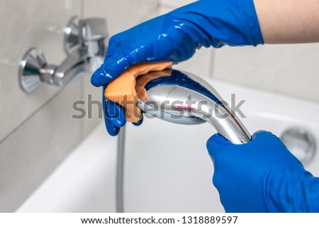 Close-up of the shower faucet and showerhead cleaning process from lime scale, white chalk sediment and stains using a commercial soap scum remover. Bathroom cleaning and disinfection Royalty-Free Stock Photo #1318889597