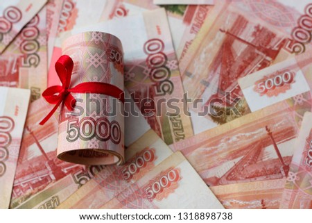 Russian money 5000 rubles twisted into a tube and tied with a ribbon, against the background of bills, the color of the year according to the version of Panton