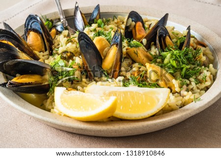 Lemon rice with mussels, midopilafo in a plate on a light tablecloth - greek dish