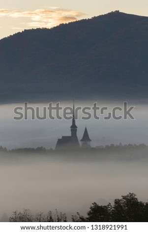 Old orthodox church surrounded by mist in the rural part of Maramures county, Romania shot before sunrise creating a scenic atmosphere