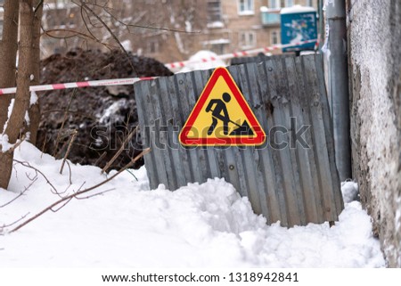 Sign road work on the fence in the yard in winter. Repair work in a residential house.