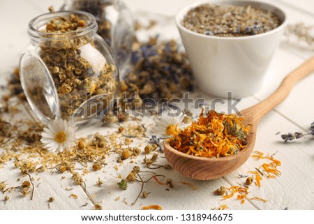 Glass jar and spoon with dried flowers on white wooden table