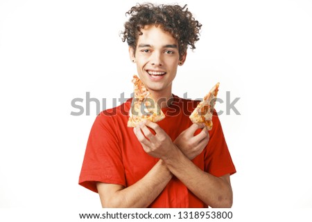 young curly guy in a red vest holding pieces of pizza in his hands and smiling at the camera