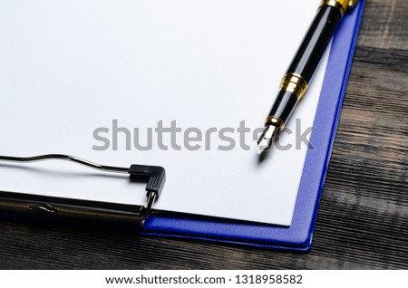 blank paper with pen in folder on wooden table in studio