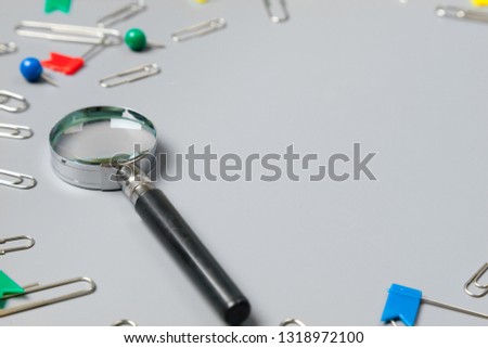 magnifying glass with paper clips on grey background.minimalism concept