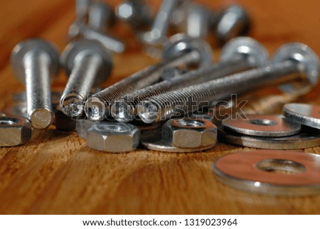 Several long screws for home workshop on a wooden surface closeup. Shallow depth of field
