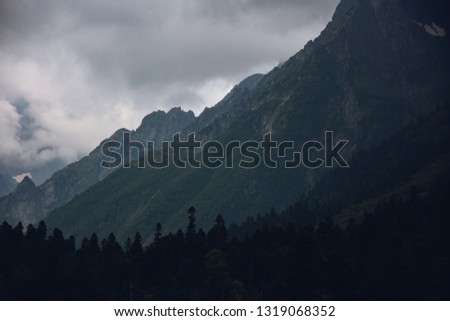 Peaks of Dombai mountains in summer rain clouds