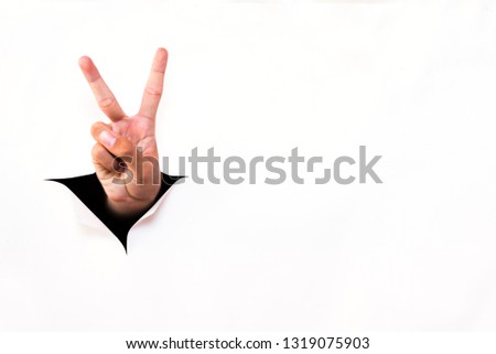 Hand pointing two fingers breakthrough white paper torn