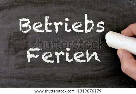 a person writing the german words Betriebsferien on a chalkboard, translate company holidays Royalty-Free Stock Photo #1319076179