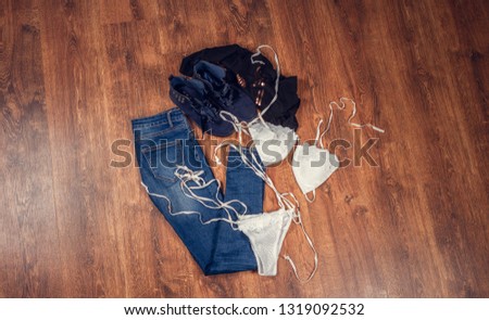 Womens clothes on wooden background. Womens jeans. Ankle boots. Bra and panties.