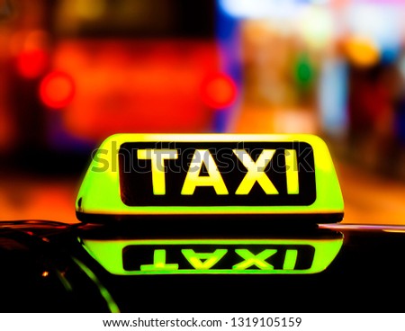 Illuminated with yellow taxi taxi sign on a car roof at night.