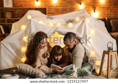Happy family reading book at home Royalty-Free Stock Photo #1319127497