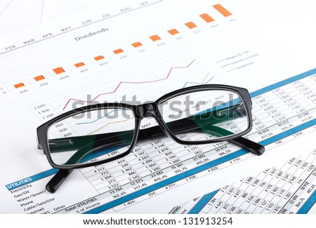 Glasses on contemporary workplace with financial papers