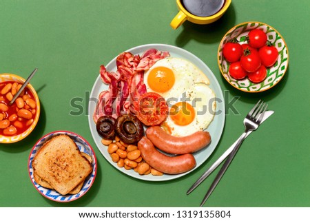 Classical English breakfast table setting styled in bright deep colors, high contrast flat lay image with a strong sunny shadow