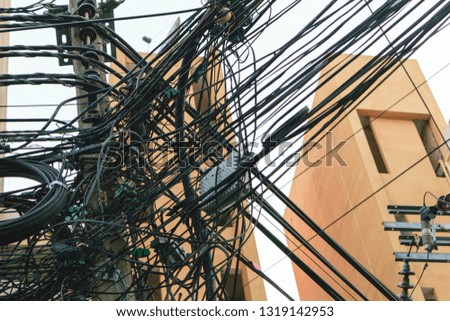 A bunch of tangled power lines or wire cable around the power poles in Thai capital Bangkok, black electricity post