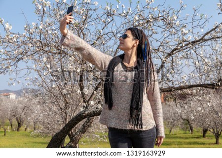 Rastafarian woman with phone in the hand taking a selfie. 