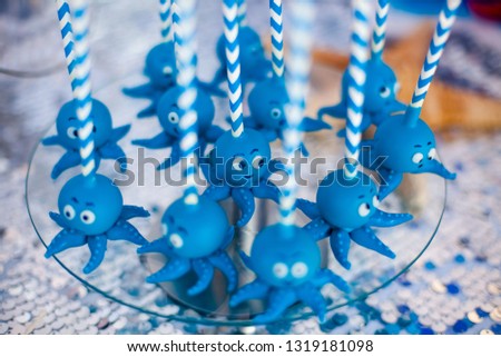 Blue cake pops funny octopuses shared on the glass round plate. Summer candy bar on the party, birthday.