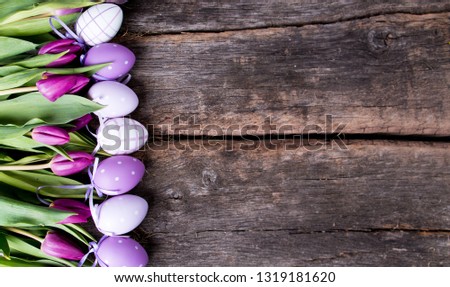 Purple tulips and easter eggs on wooden table with free space for text. Holiday concept