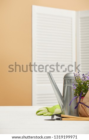 purple flowers in flowerpot with paper and watering can