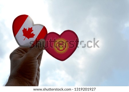 Hand holds a heart Shape Canada and Kyrgyzstan flag, love between two countries