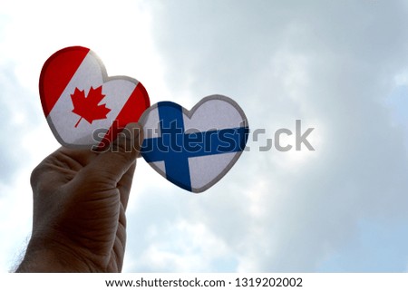 Hand holds a heart Shape Canada and Finland flag, love between two countries