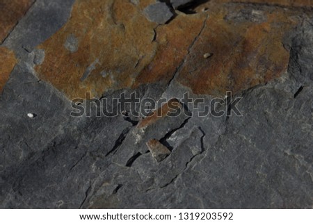 Closeup abstract texture background broken shale with cracks and chips and alternating layers of blue and orange stratification. 