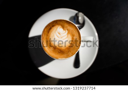 Top view of a beautiful latte hot coffee in a white cup with latte art. Elegant top of view picture of a cappuccino with sun light.