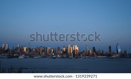 Midtown Manhattan skyline.  This photo shows the New York City skyline at sunset with the building reflecting the colors of sunset as night fades in.  