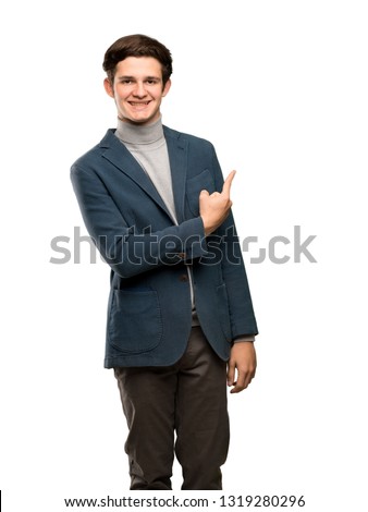 Teenager man with turtleneck pointing to the side to present a product over isolated white background