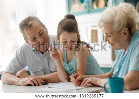 Granny helps a grandaughter to draw a picture. Entertainment, talent development, art skills and vision.