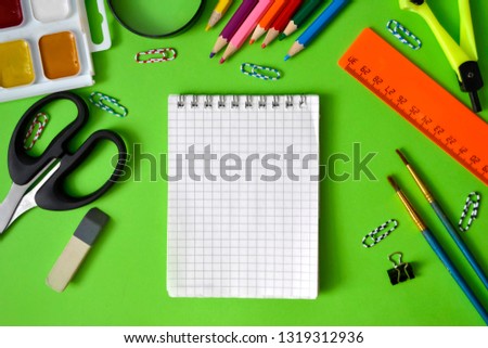 school subjects: pens, notebooks, pencils, paper clips on a light green background