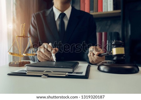 Lawyeradvice and justice concept, counselor lawyer or notary working on a documents and report of the important case and wooden gavel, brass scale on table in courtroom