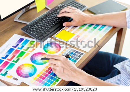 Graphic designer or creative holding Mouse and do his work material color pantone swatch samples art tools at desk in office 