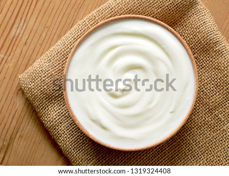 Delicious yogurt scene with wooden bowl and sackcloth. Closeup shot of healthy fresh yogurt. Top view.