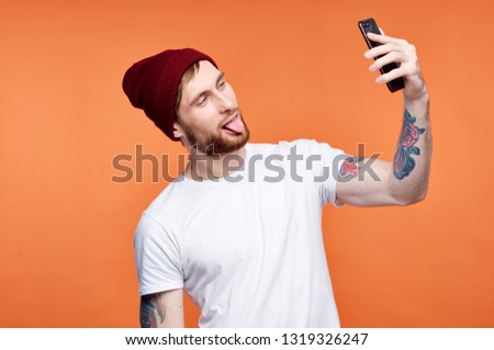 A barking handsome man relieves himself on the phone on an orange background