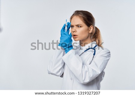 Woman doctor in white coat in blue gloves with a syringe in her hands
