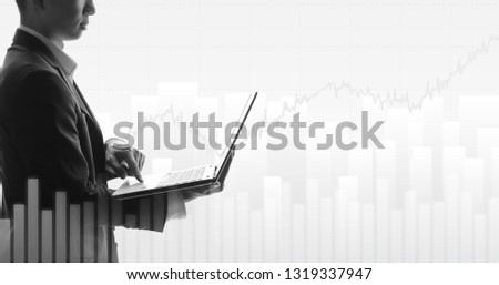 widescreen of Business man using laptop with abstract financial chart and uptrend line graph in stock market on black and white color background