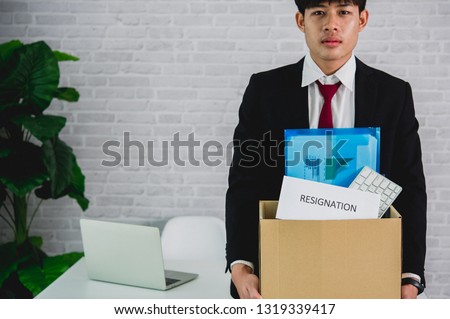 Picture of a businessman holding a brown cardboard box in the box with a resignation letter Concept of resignation, new job change