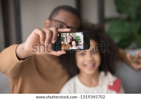 Happy african dad taking selfie with kid daughter on cellphone, smiling black father holding phone making pic on modern smartphone camera, daddy and child focus portrait picture on mobile display